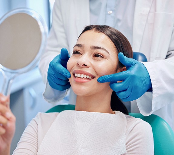 happy patient looking in a mirror and the dentist pointing to her smile