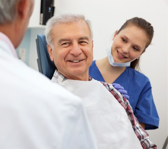 Senior dental patient smiling at dentist and assistant