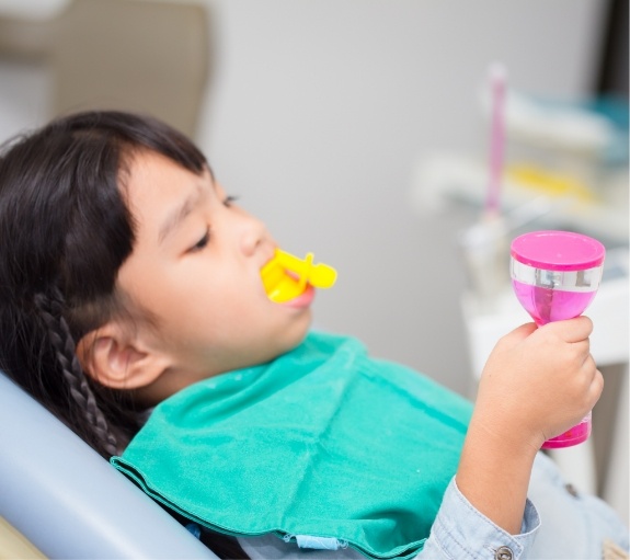 Young girl in dental chair with fluoride trays on her teeth