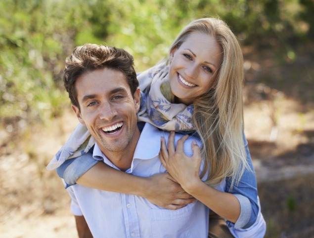 Smiling man and woman holding each other outdoors