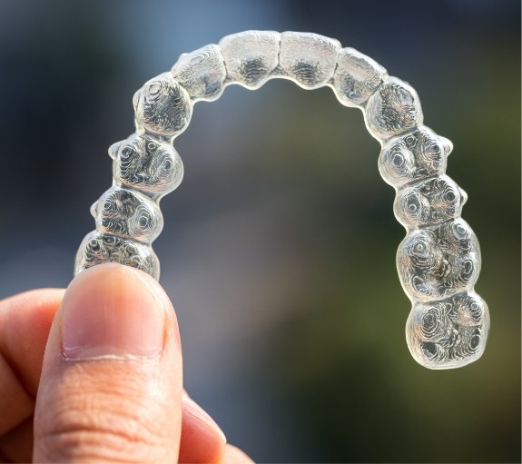 Hand holding a SureSmile clear aligner