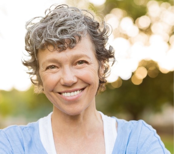 Senior woman in blue shirt smiling outdoors