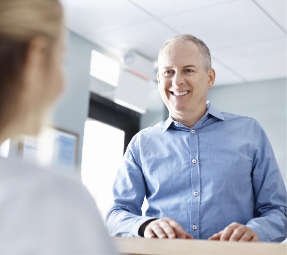 Man smiling at dental office receptionist