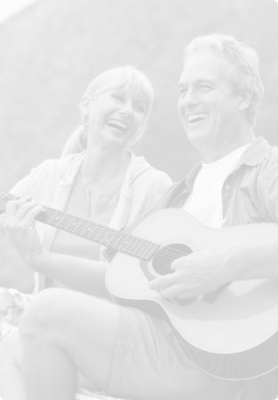 Older man playing acoustic guitar next to smiling woman