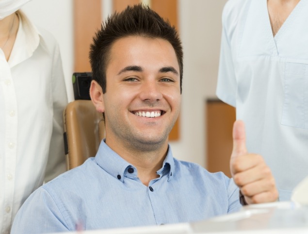 Man in dental chair smiling and giving thumbs up