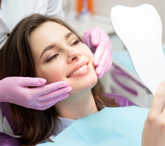 Young woman looking at her smile in mirror during dental checkup