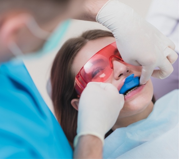 Young woman in dental chair with fluoride trays on her teeth