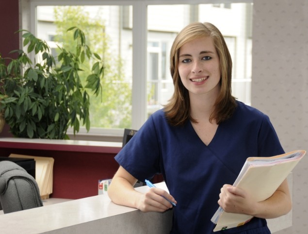 Smiling dental team member standing by front desk