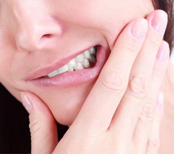 Close up of person holding their cheek in pain