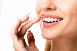 Woman lightly touching her teeth as she smiles